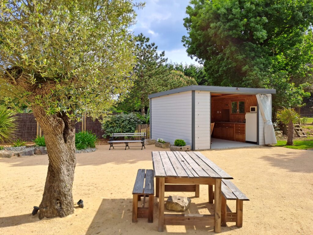 Cuisine d'été équipée en extérieur pour les hôtes avec espace repas sous pergola à [Les Sables d'Olonne]